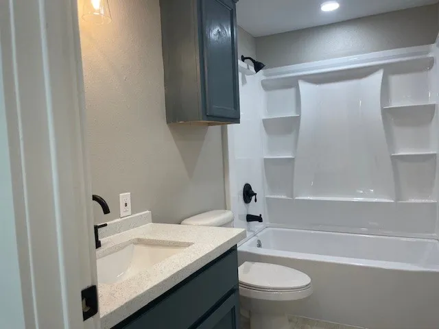 a bathroom with a granite countertop toilet a sink and a bathtub