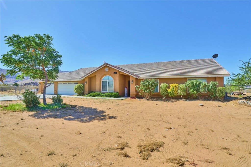 24977 Keator Road Apple Valley, CA 92307 - Photo 1 of 1 a front view of a house with a dirt yard and a large tree