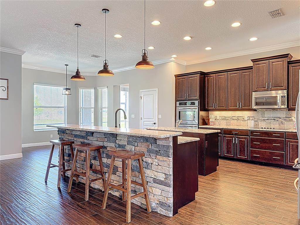 2350 Virgil Hall Road Lithia, FL 33547 - Photo 12 of 52 a kitchen with stainless steel appliances granite countertop wooden floors and wooden cabinets