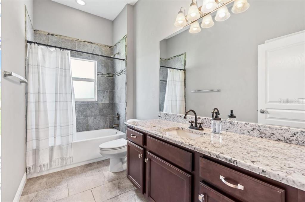 2350 Virgil Hall Road Lithia, FL 33547 - Photo 20 of 52 a bathroom with a granite countertop sink a toilet a mirror and shower