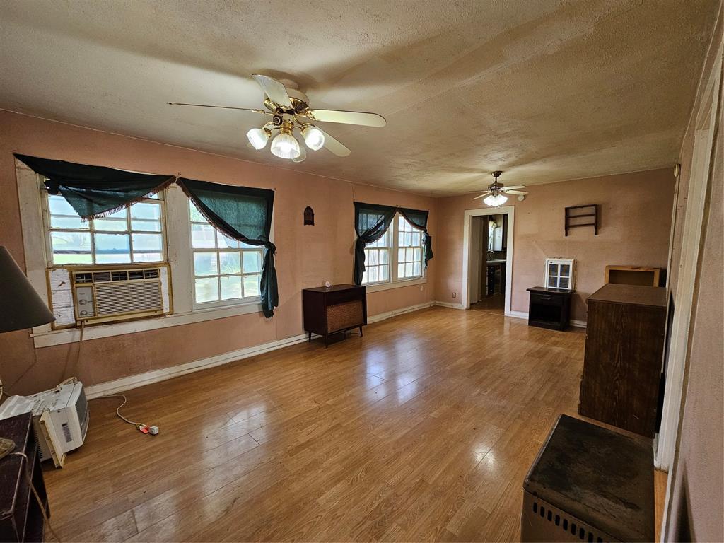 127 East Morgan Street Pilot Point, TX 76258 - Photo 11 of 25 Unfurnished living room with a ceiling fan, wood finished floors, and a textured ceiling