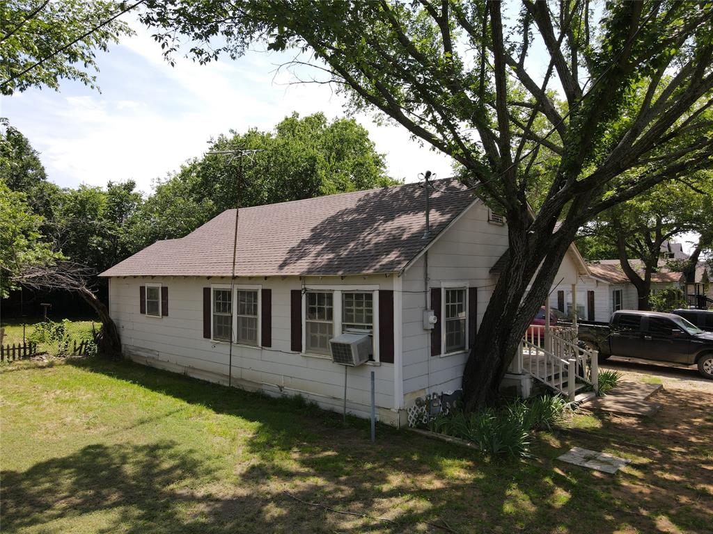 127 East Morgan Street Pilot Point, TX 76258 - Photo 20 of 25 View of front facade featuring a shingled roof, a front lawn, and cooling unit