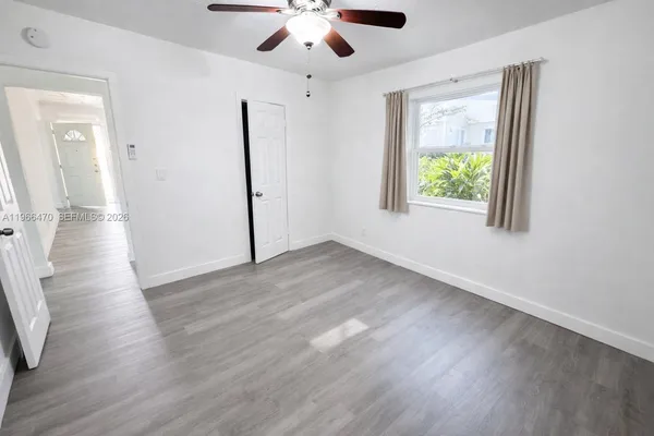 an empty room with wooden floor chandelier fan and windows