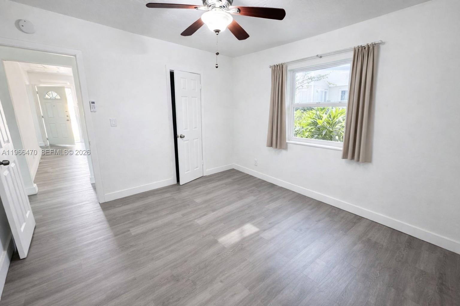 3450 Southwest 7th Street, Unit 3450 Miami, FL 33135 - Photo 4 of 7 an empty room with wooden floor chandelier fan and windows