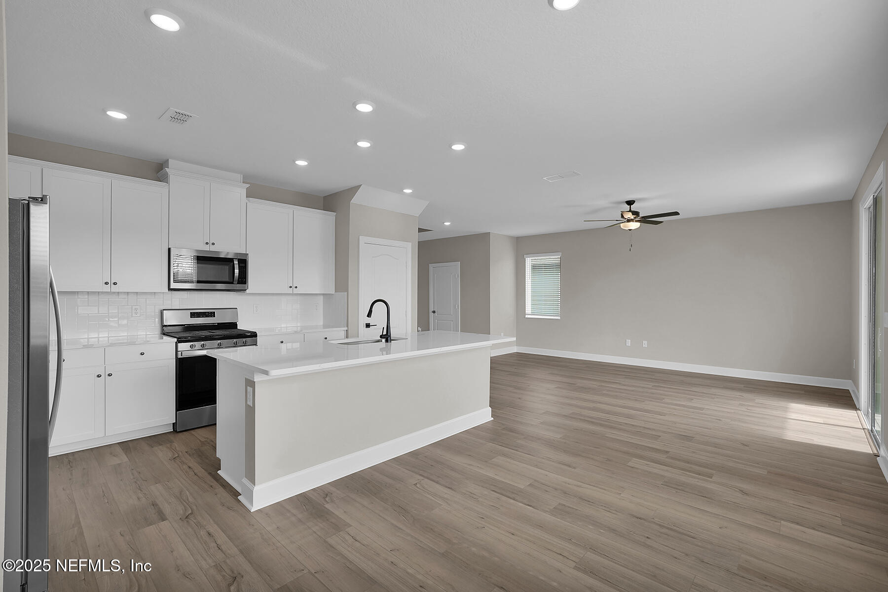 3987 Gareys Ferry Way Middleburg, FL 32068 - Photo 10 of 25 a large white kitchen with a refrigerator a stove top oven a sink and dishwasher with wooden floor