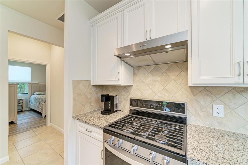 7013 Hanover Court Lakewood Ranch, FL 34202 - Photo 14 of 64 a kitchen with white cabinets and a stove top oven