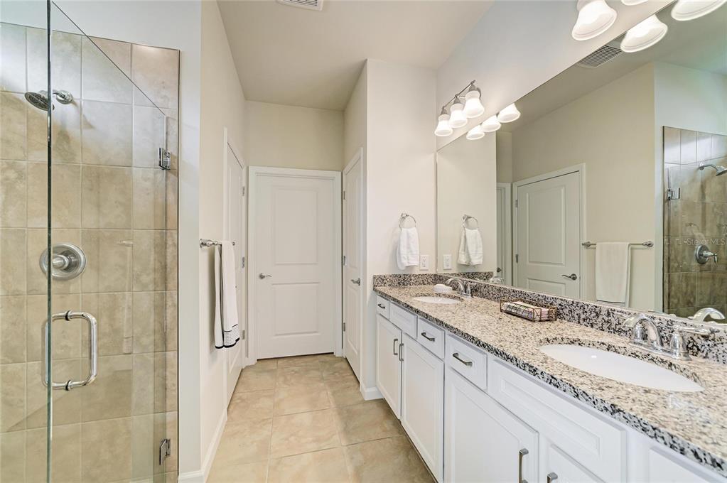 7013 Hanover Court Lakewood Ranch, FL 34202 - Photo 29 of 64 a spacious bathroom with a granite countertop sink a mirror and a shower
