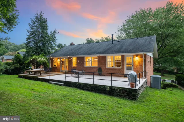 a backyard of a house with lots of plants and large tree