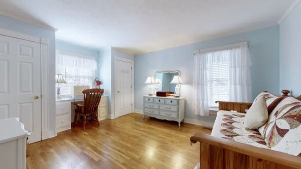 a living room with couches and dresser with wooden floor