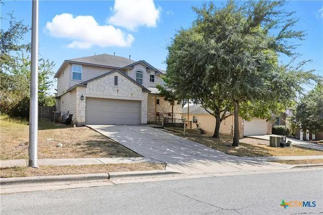 a view of a house with a yard and large tree