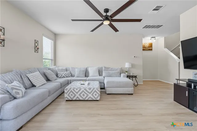 a living room with furniture a flat screen tv and a ceiling fan