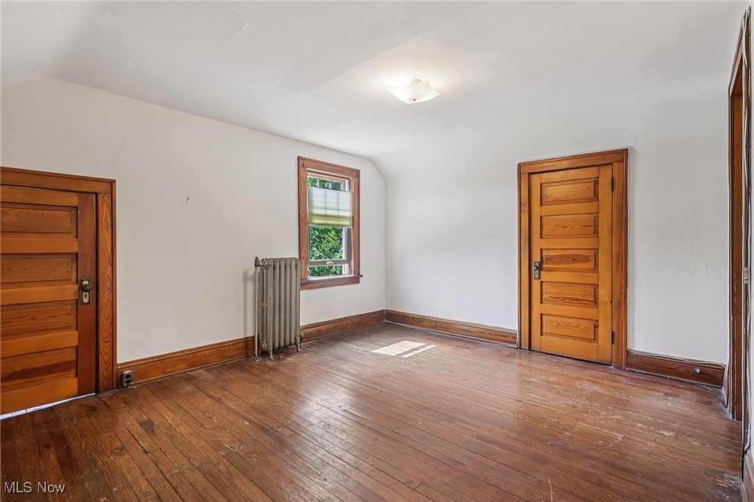 3075 Scarborough Road Cleveland, OH 44118 - Photo 36 of 46 Unfurnished room featuring lofted ceiling, radiator heating unit, and dark wood-type flooring