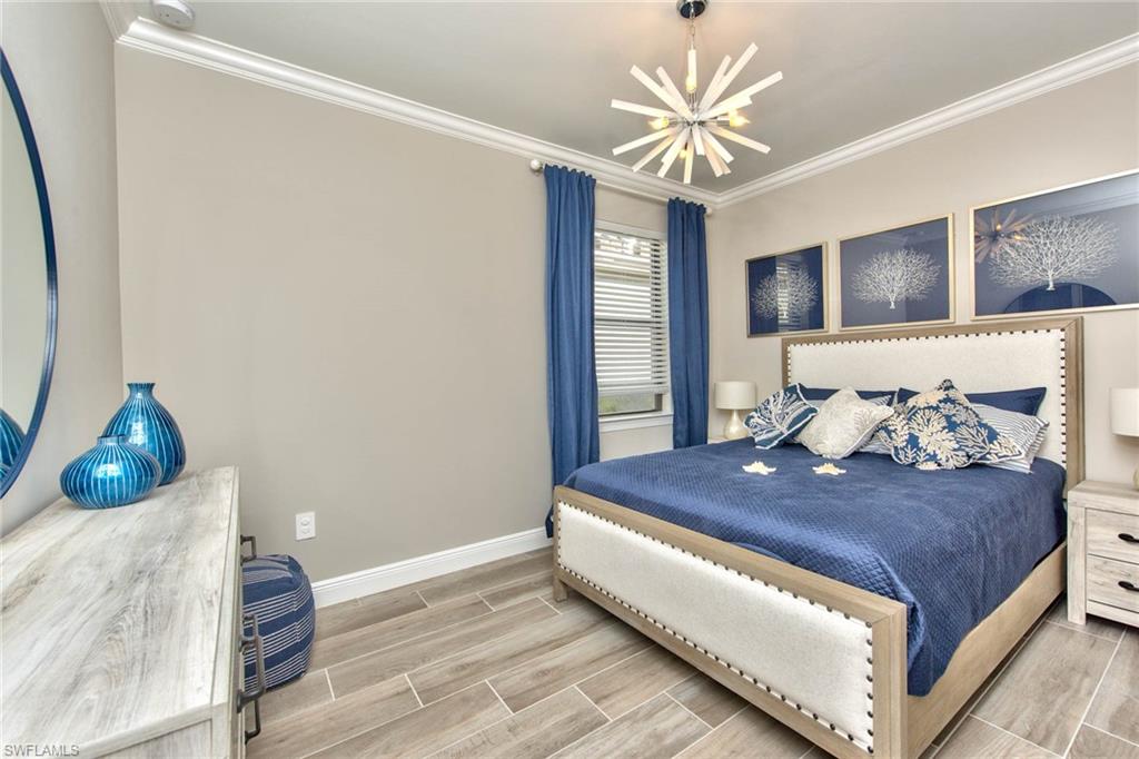 9761 Willet Court Naples, FL 34120 - Photo 17 of 34 a bed sitting in a bedroom next to a window with a chandelier