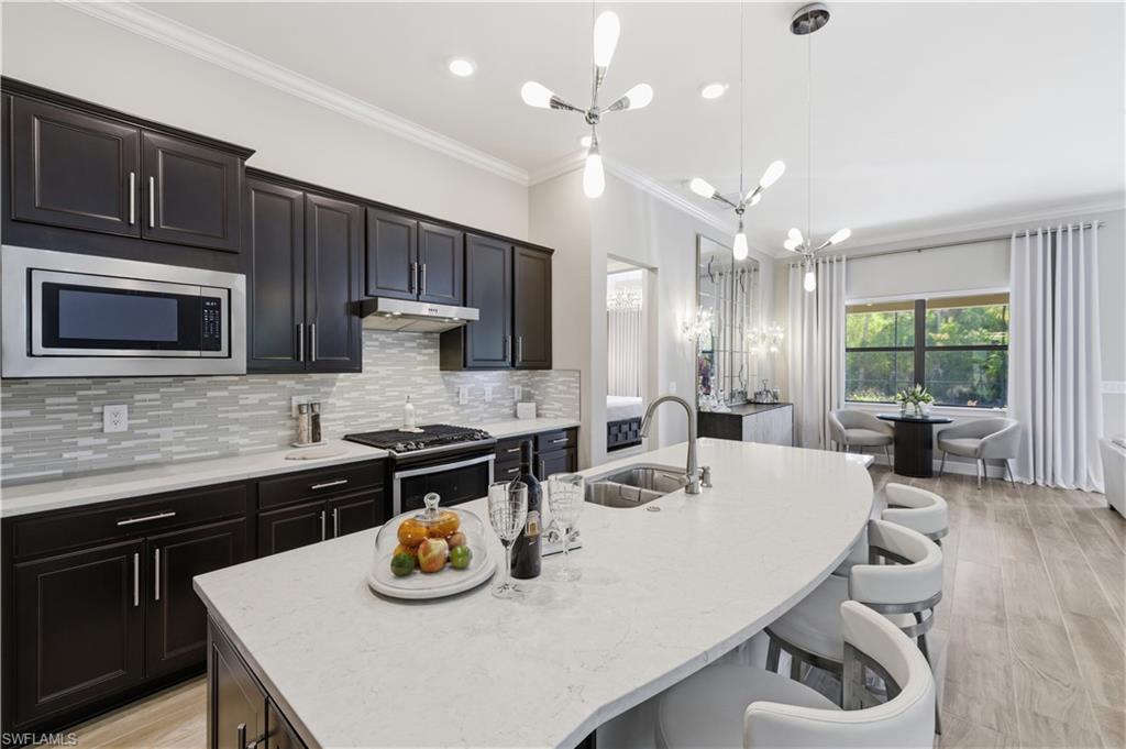 9761 Willet Court Naples, FL 34120 - Photo 20 of 44 a kitchen with a sink a stove and chairs