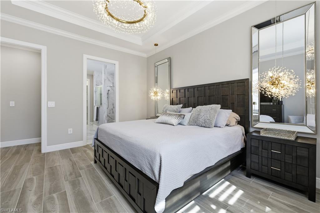 9761 Willet Court Naples, FL 34120 - Photo 27 of 44 a bedroom with a bed and a chandelier