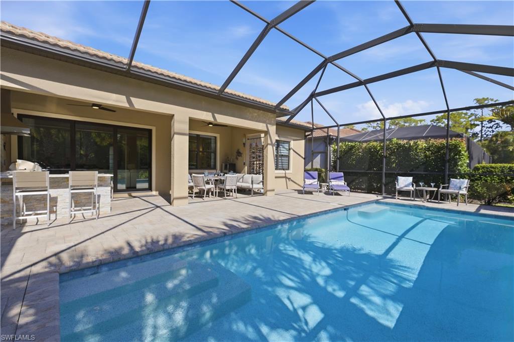 9761 Willet Court Naples, FL 34120 - Photo 33 of 44 a view of a patio with dining table and chairs under an umbrella