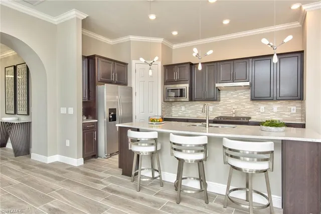 a kitchen with stainless steel appliances kitchen island granite countertop a dining table chairs sink and cabinets