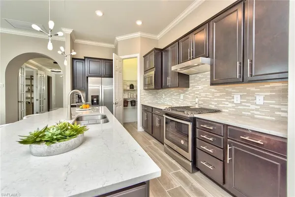 a large kitchen with kitchen island a large counter space a sink stainless steel appliances and cabinets