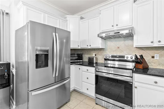 a kitchen with stainless steel appliances white cabinets and a refrigerator
