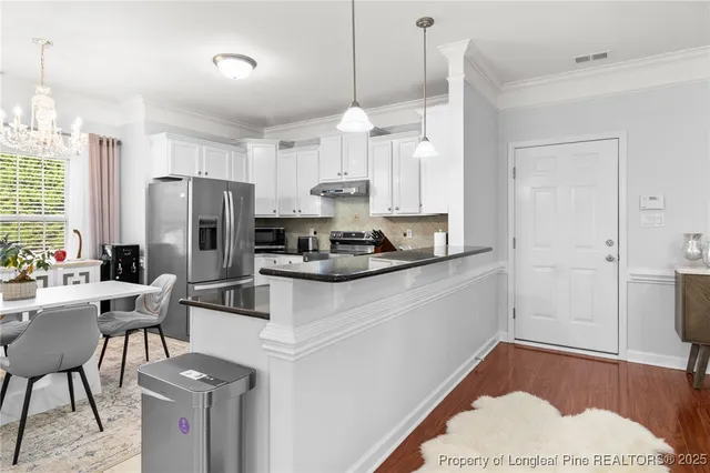 a kitchen with a refrigerator a stove a sink dishwasher and white cabinets with wooden floor