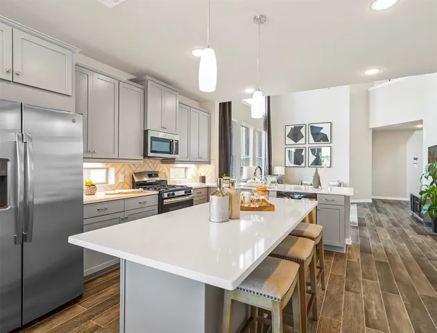 a kitchen with sink a refrigerator and chairs