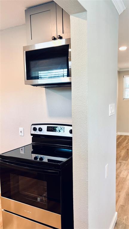 4603 Junius Street, Unit 8 Dallas, TX 75246 - Photo 7 of 16 Kitchen with stainless steel appliances, wood finished floors, and crown molding