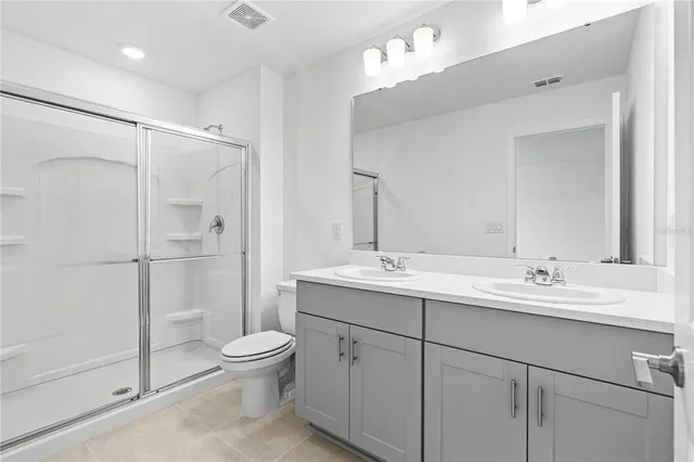 a bathroom with a double vanity sink toilet mirror and shower