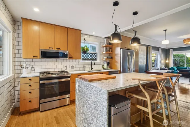 a kitchen with stainless steel appliances granite countertop a stove a sink island and a refrigerator with wooden floor