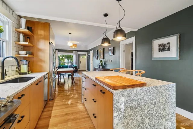 a dining hall with stainless steel appliances granite countertop a stove a sink dishwasher and cabinets with wooden floor