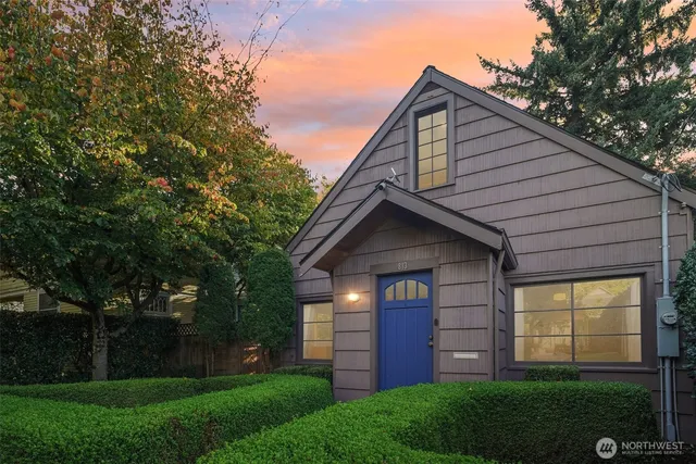 a view of a house with a small yard and a large tree