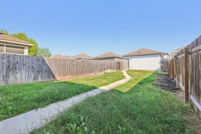 a view of a house with a yard and wooden fence