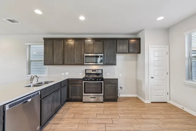 a large kitchen with stainless steel appliances granite countertop a stove and a sink