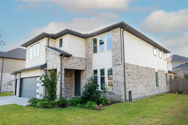 a view of a house with brick walls and a yard with plants