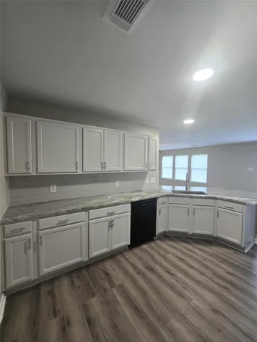 a kitchen with granite countertop a sink cabinets and wooden floor