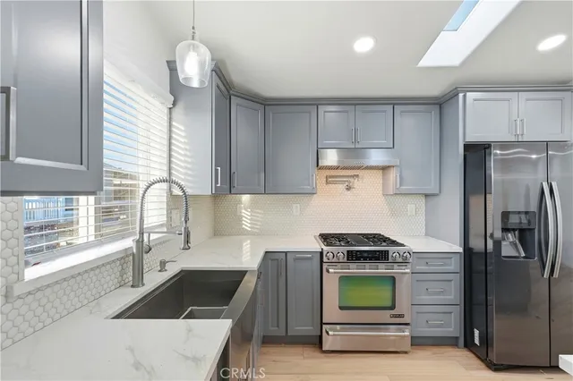 a kitchen with granite countertop a refrigerator and a stove top oven