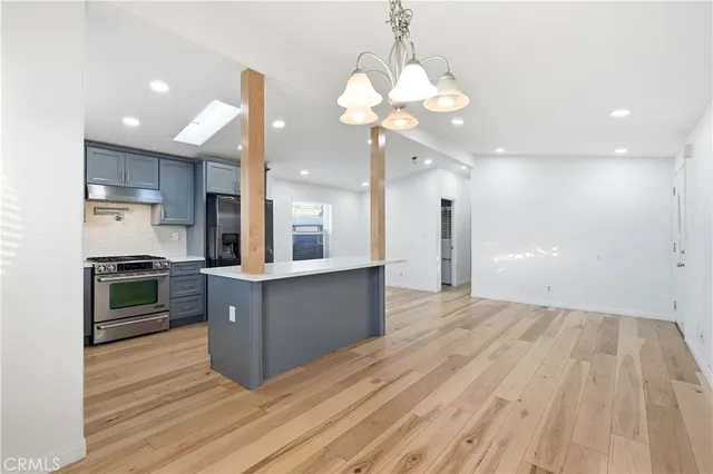 a kitchen with stainless steel appliances kitchen island granite countertop a stove a refrigerator a sink a oven with a dining table and chairs