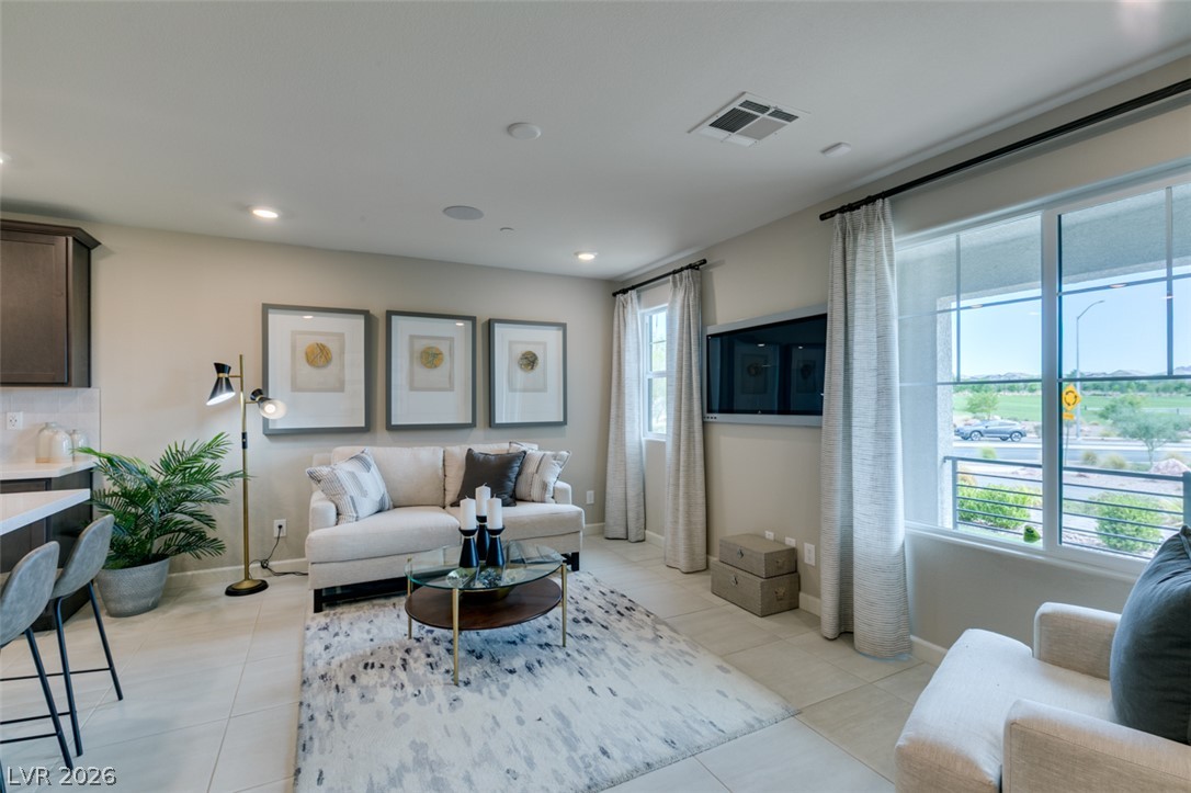 653 Pickled Pepper Place Henderson, NV 89011 - Photo 7 of 35 A well-lit living area features tiled flooring and large windows, offering views of the surrounding landscape.