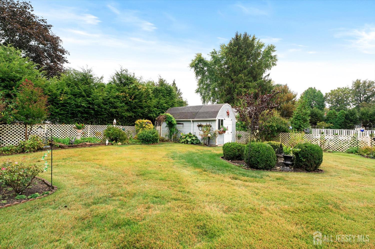 66 Rutgers Avenue Hamilton, NJ 08619 - Photo 30 of 31 a yellow house with a big yard and a large trees with wooden fence