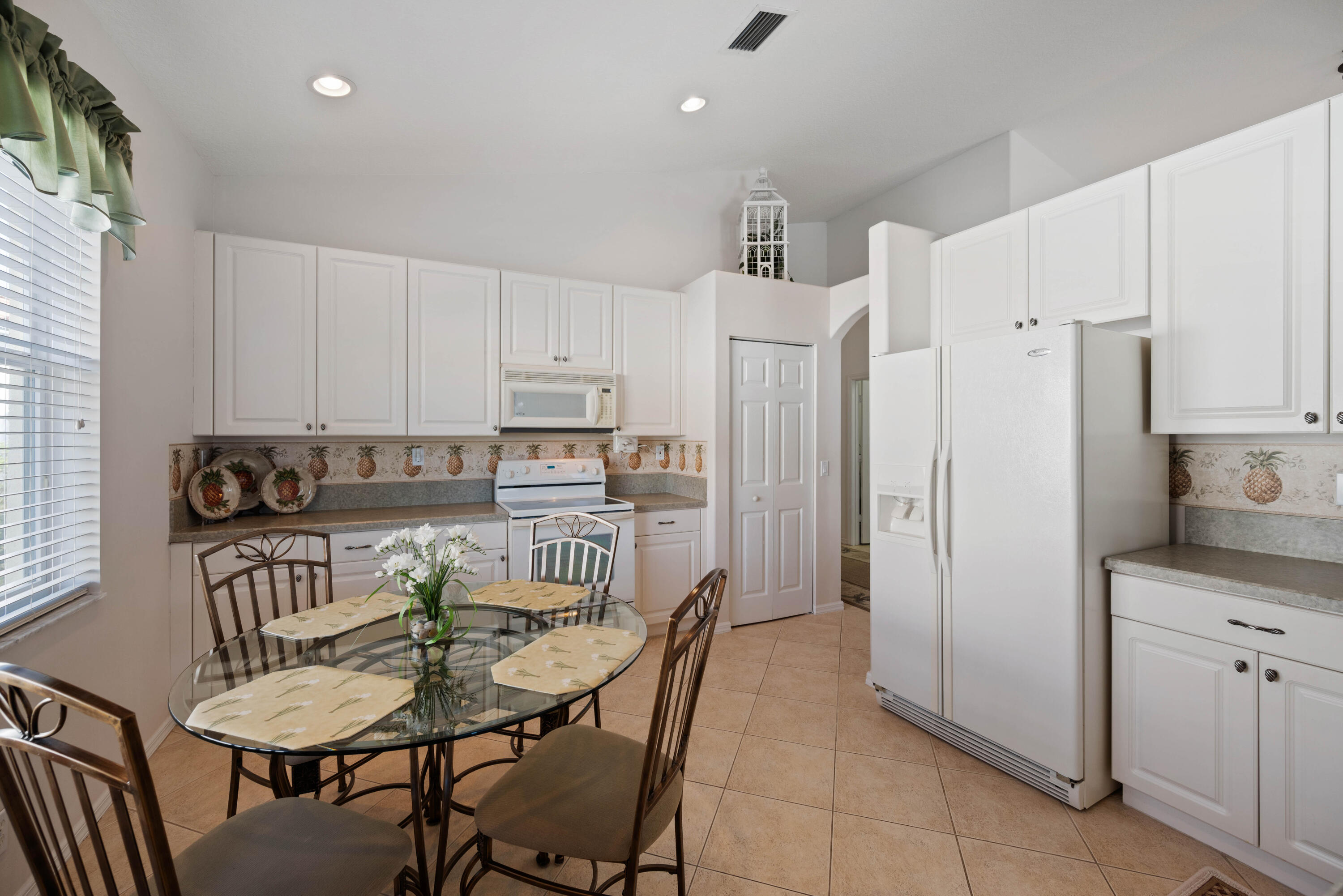 2096 Northwest Marsh Rabbit Lane Jensen Beach, FL 34957 - Photo 5 of 38 a kitchen with stainless steel appliances a refrigerator a stove a dining table and chairs