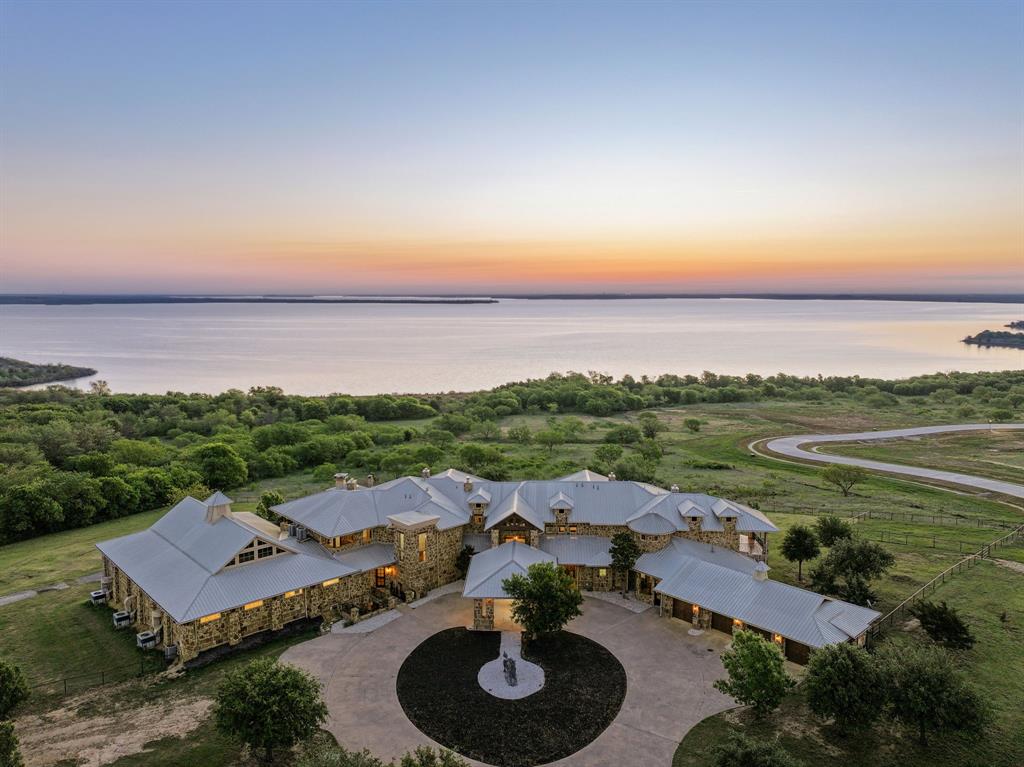 Expansive estate featuring a stone exterior, multiple gabled metal roofs, and a circular drive
