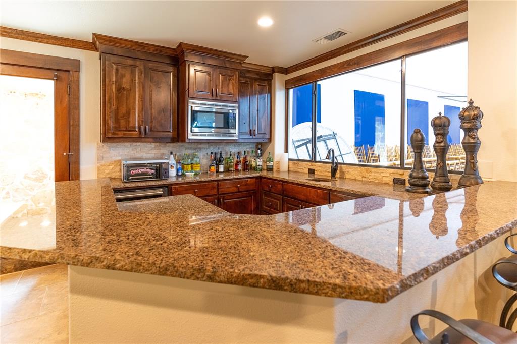1180 McReynolds Road Sanger, TX 76266 - Photo 27 of 36 a kitchen with kitchen island granite countertop a sink and a counter top space