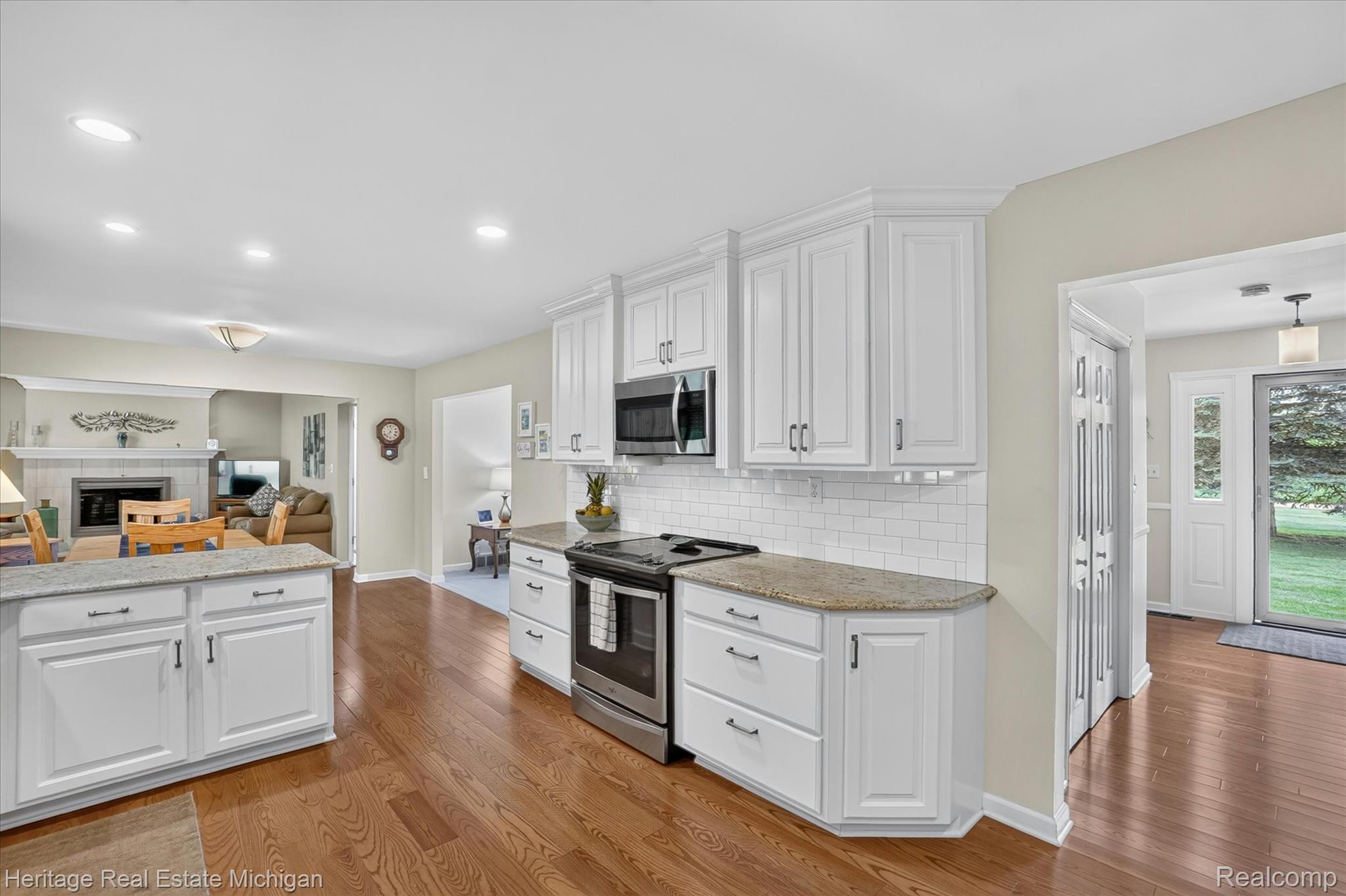 14038 North Hogan Road Linden, MI 48451 - Photo 19 of 53 Kitchen featuring white cabinetry with dark hardware, granite countertops, subway tile backsplash, and stainless steel appliances