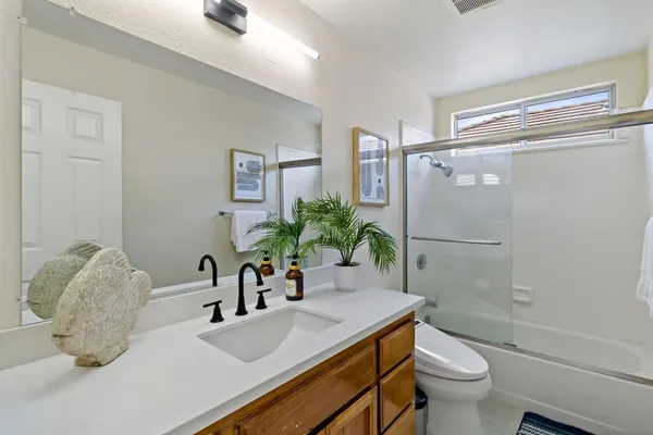 a bathroom with a granite countertop sink a toilet and shower