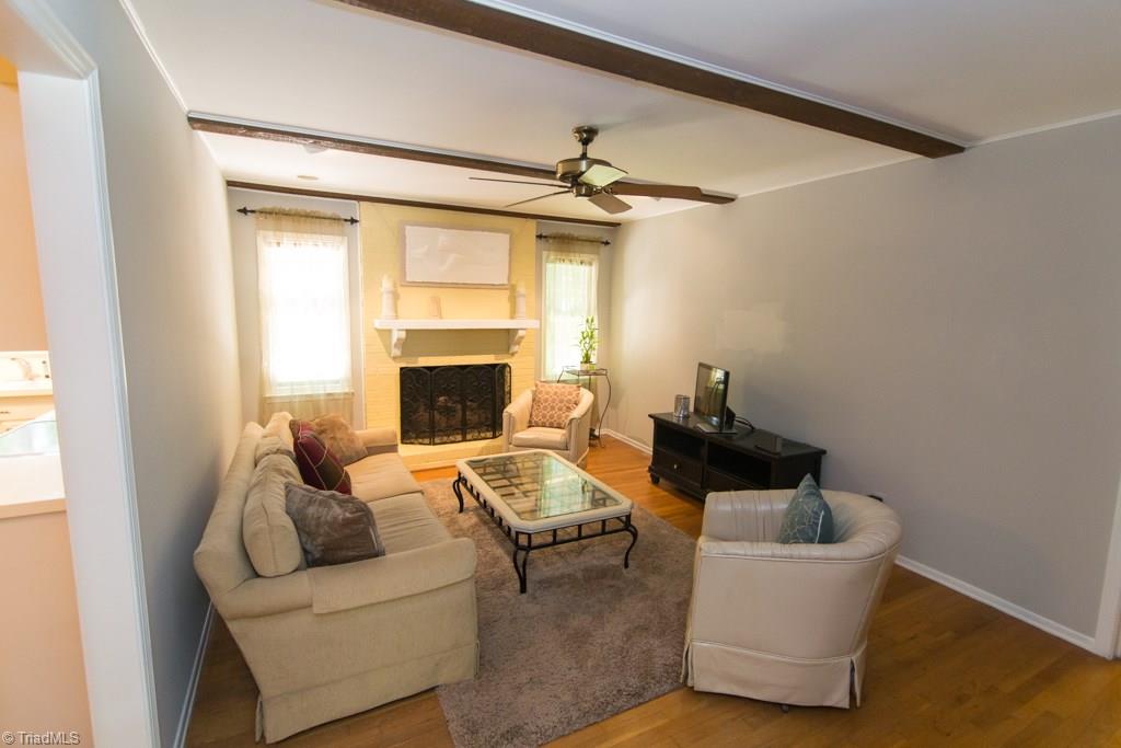 2704 Applegate Road Greensboro, NC 27455 - Photo 4 of 15 Den with wood floors, fireplace, and ceiling beams.