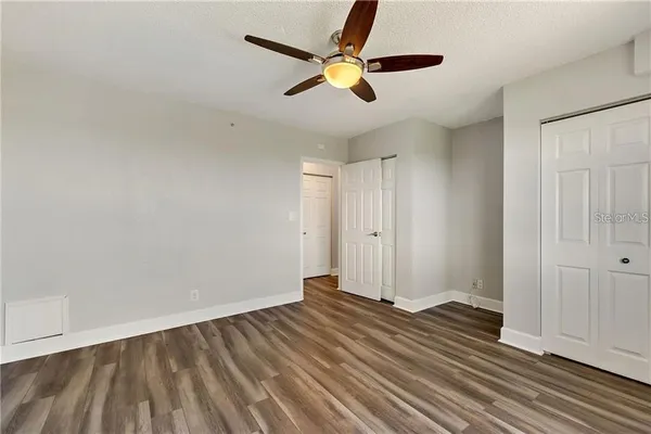 a view of empty room with wooden floor and kitchen