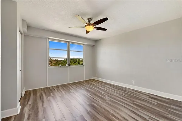 an empty room with wooden floor and windows