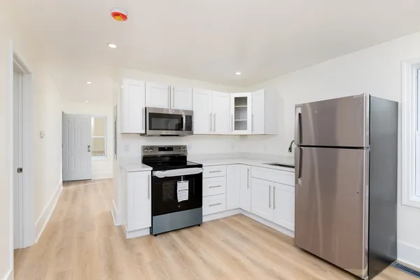 a kitchen with granite countertop a refrigerator and a stove top oven