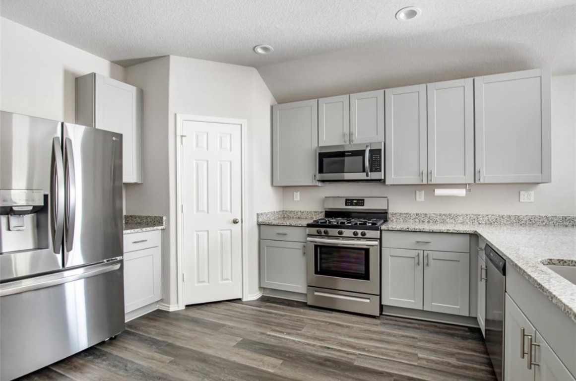 10031 Spring Creek Road Cleveland, TX 77327 - Photo 11 of 18 a kitchen with cabinets stainless steel appliances and wooden floor