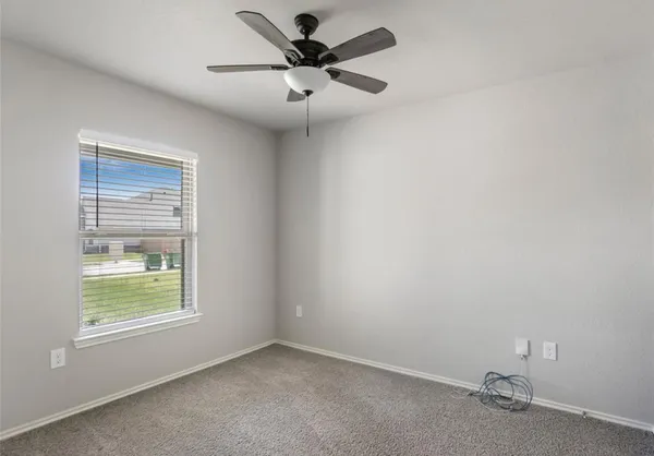 an empty room with a window and a fan