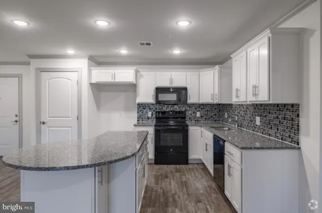 a kitchen with kitchen island granite countertop stainless steel appliances stove microwave and cabinets
